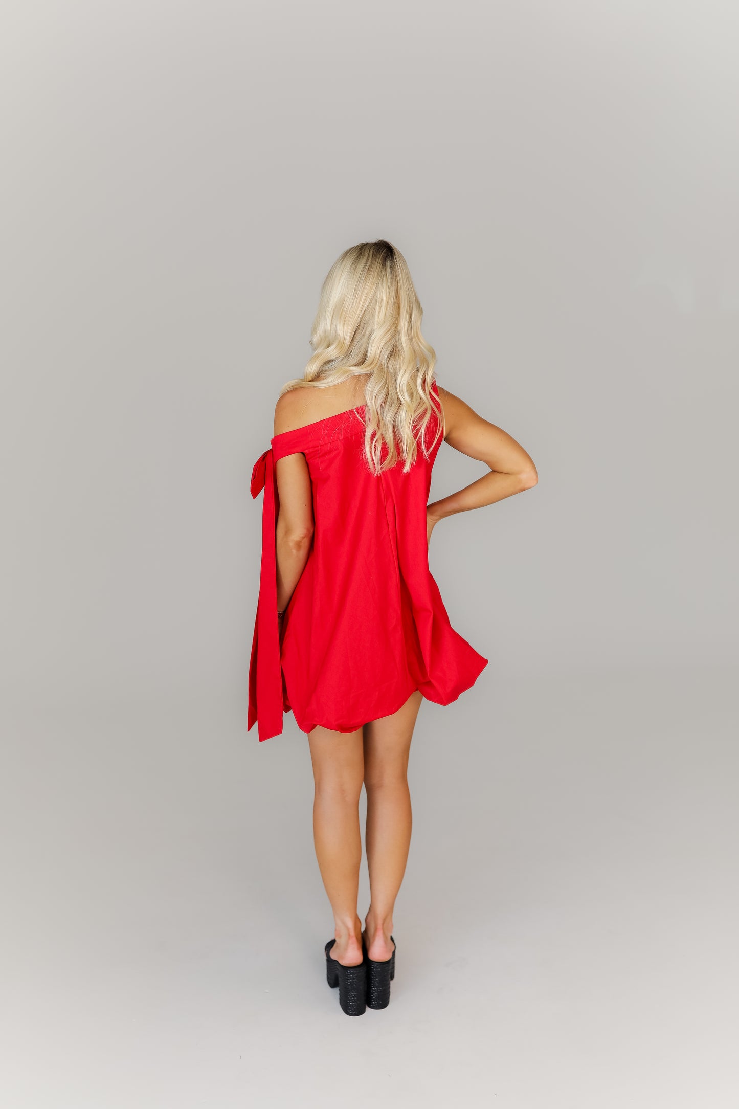 Back of red mini dress with tie straps and flowy bubble hem silhouette