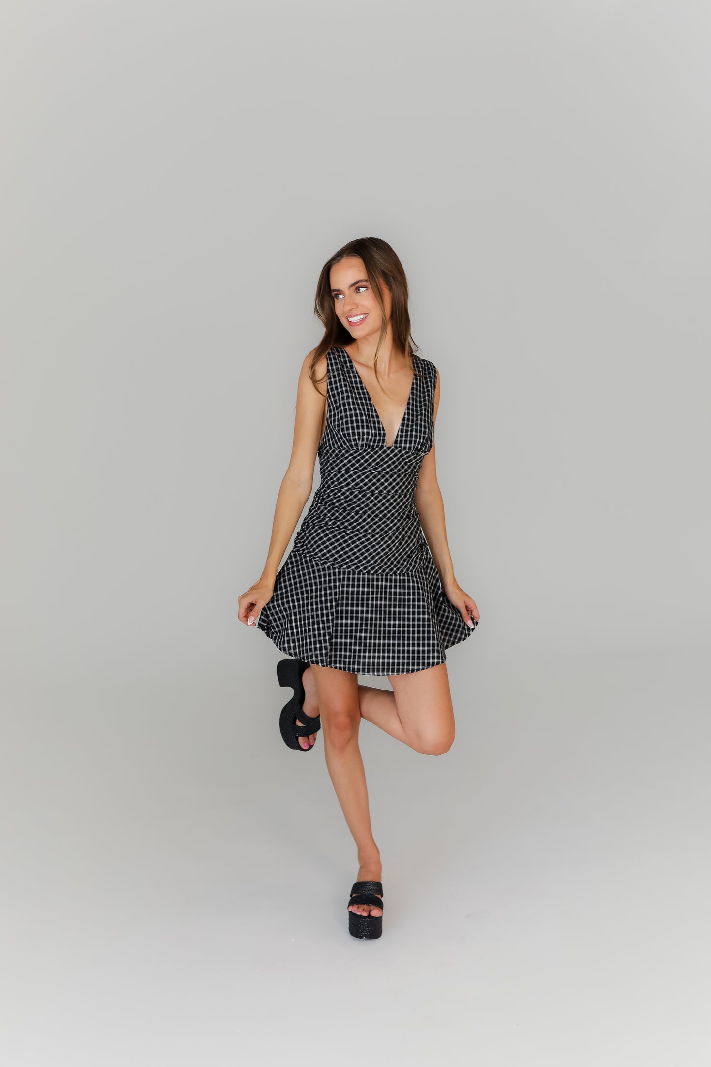 Woman wearing a black and white plaid dress on a gray background