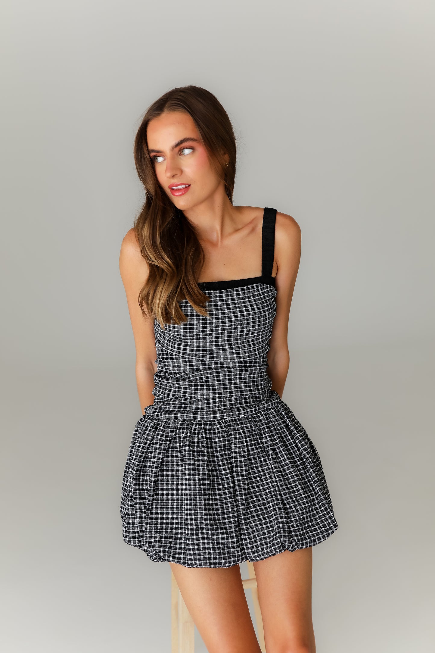 Woman wearing a black and white checkered dress against a plain background