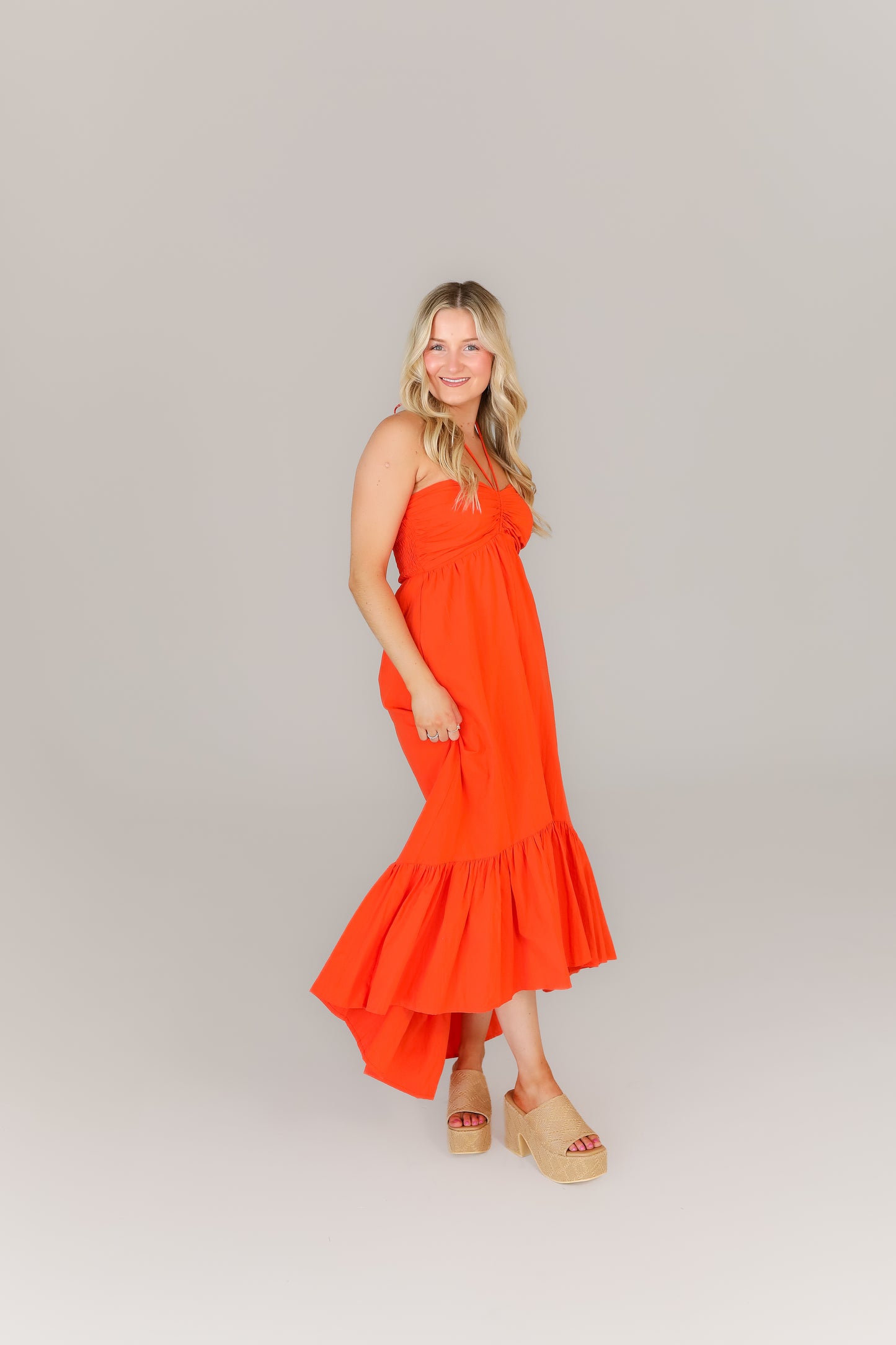 Model in tiered orange dress, ideal for sorority events