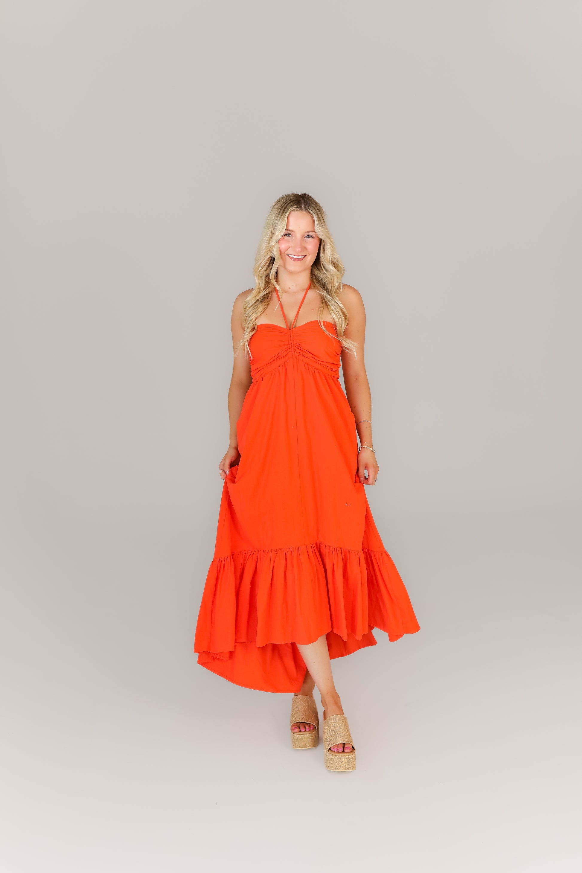 Woman wearing orange flowy midi dress perfect for football season