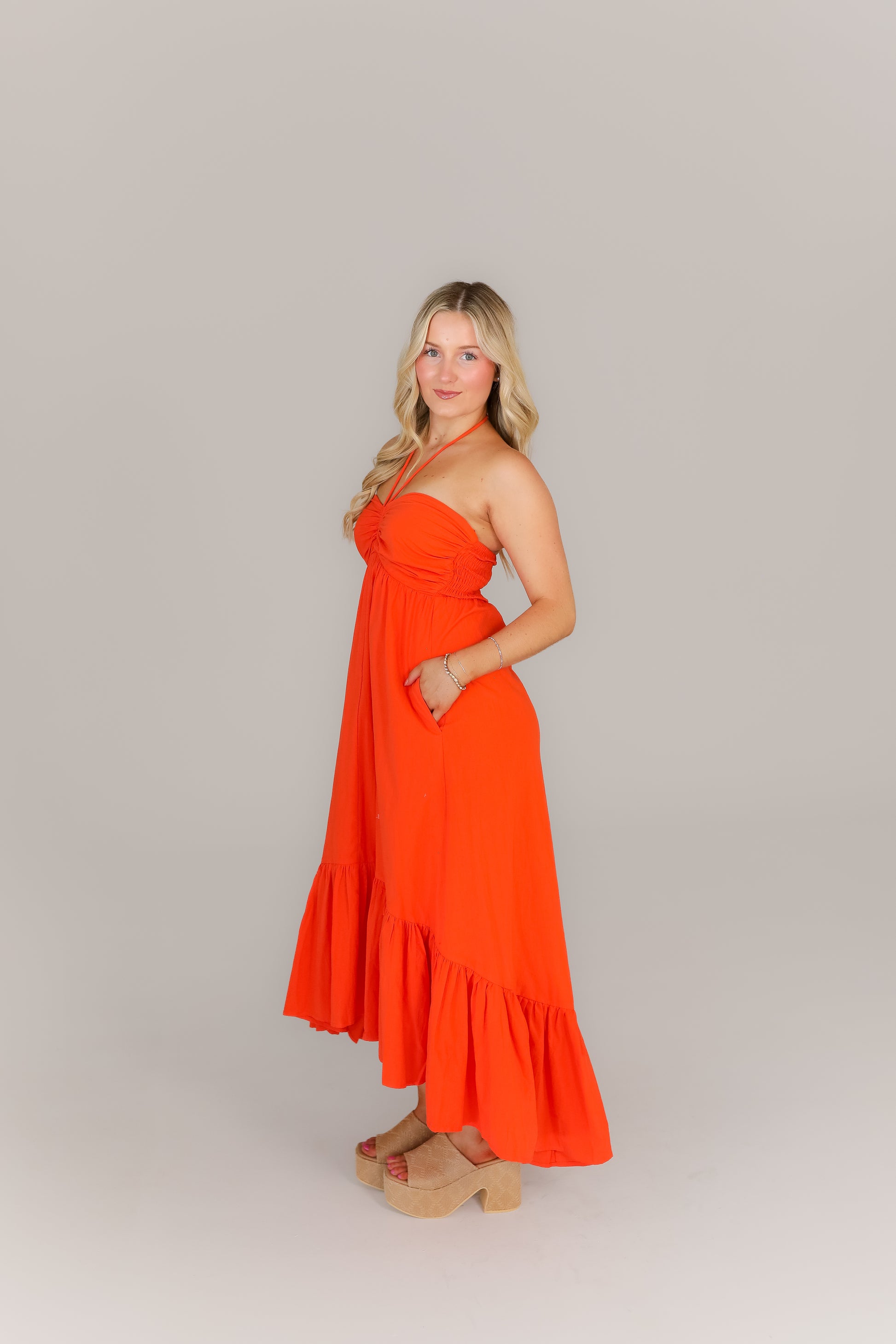Side view of orange boutique midi dress styled for night out