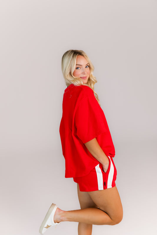 Model posing in oversized red top and shorts two-piece outfit