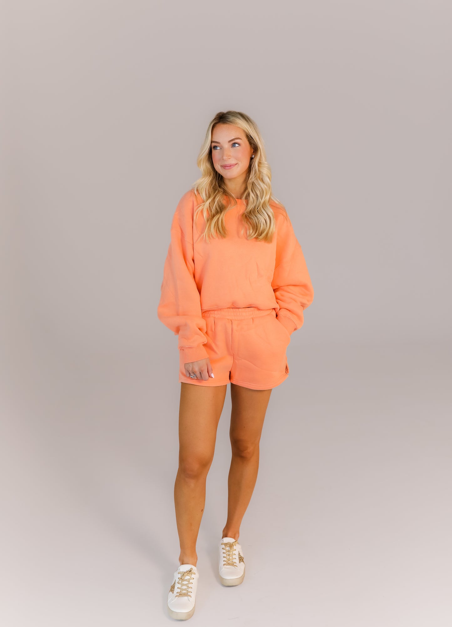 Model wearing peach oversized sweatshirt and matching shorts set
