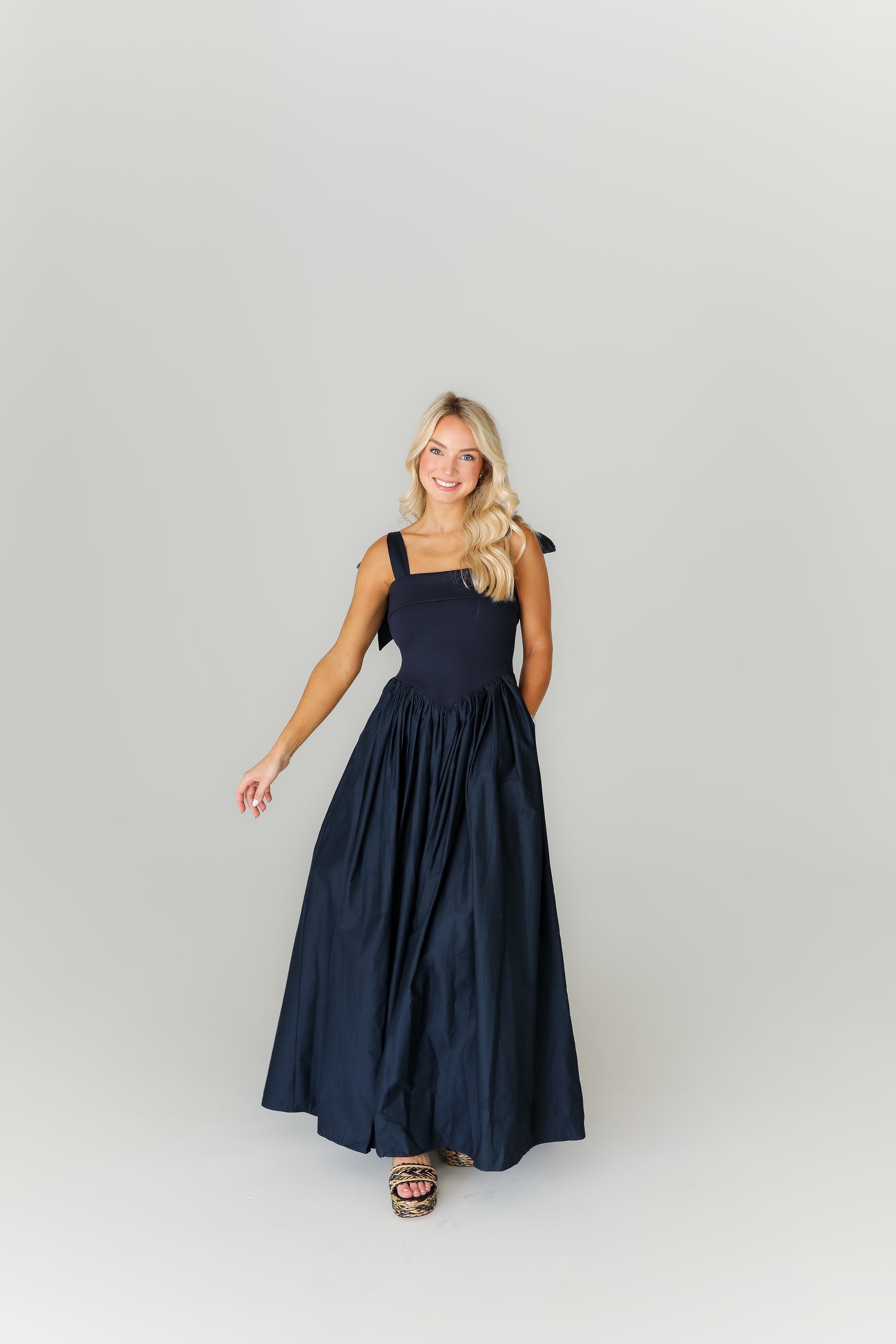 Woman wearing a navy blue dress on a plain background
