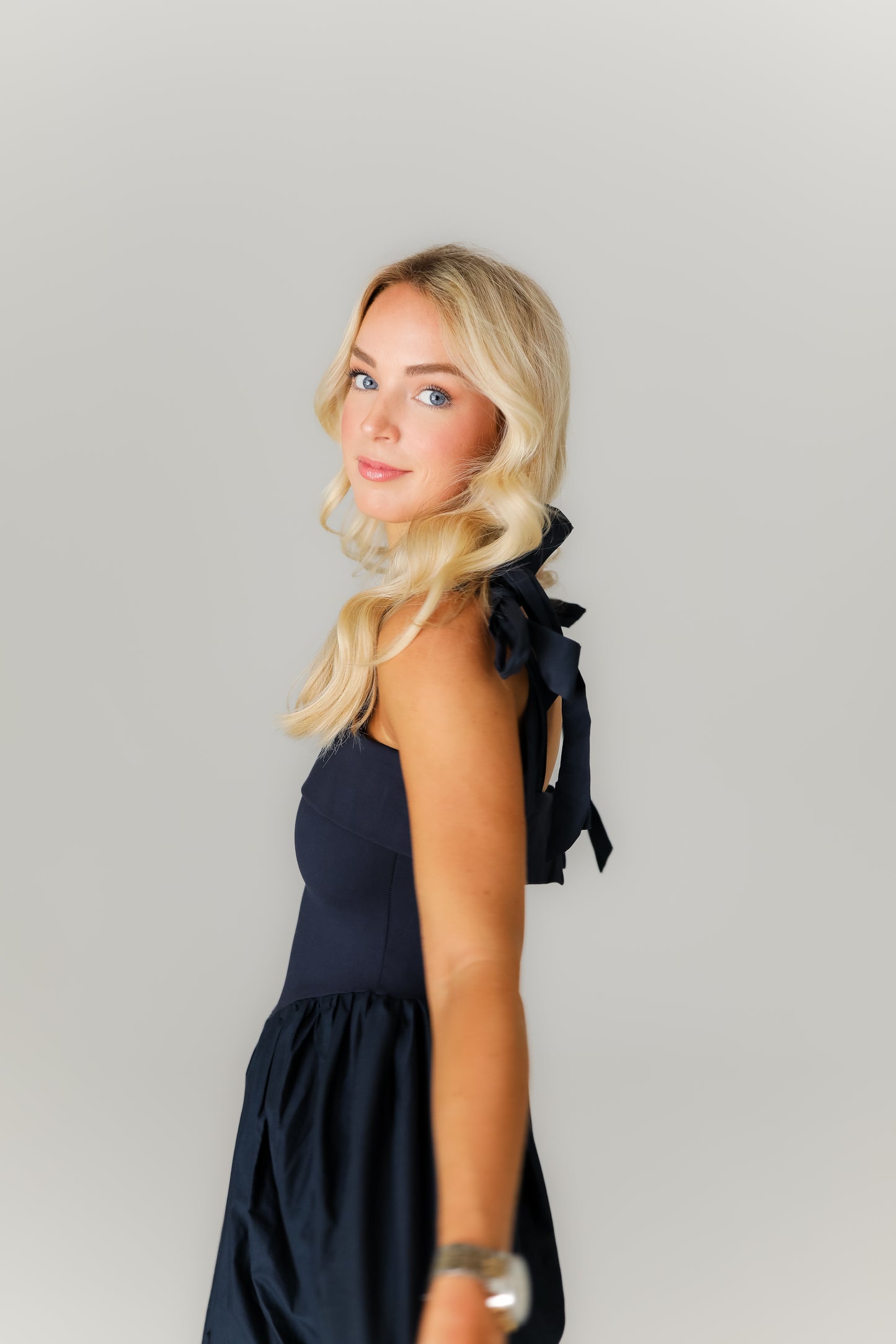 Woman wearing a navy blue dress with ruffled sleeves against a plain background