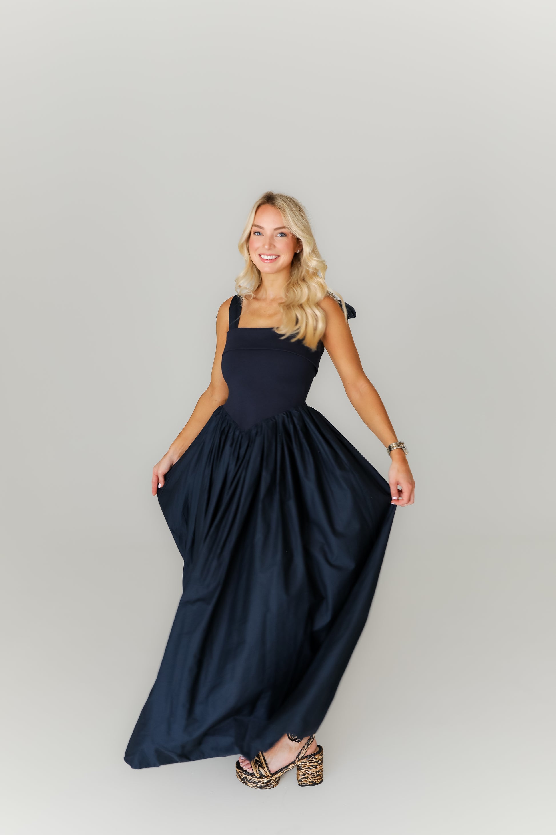 Woman wearing a navy blue dress on a plain background