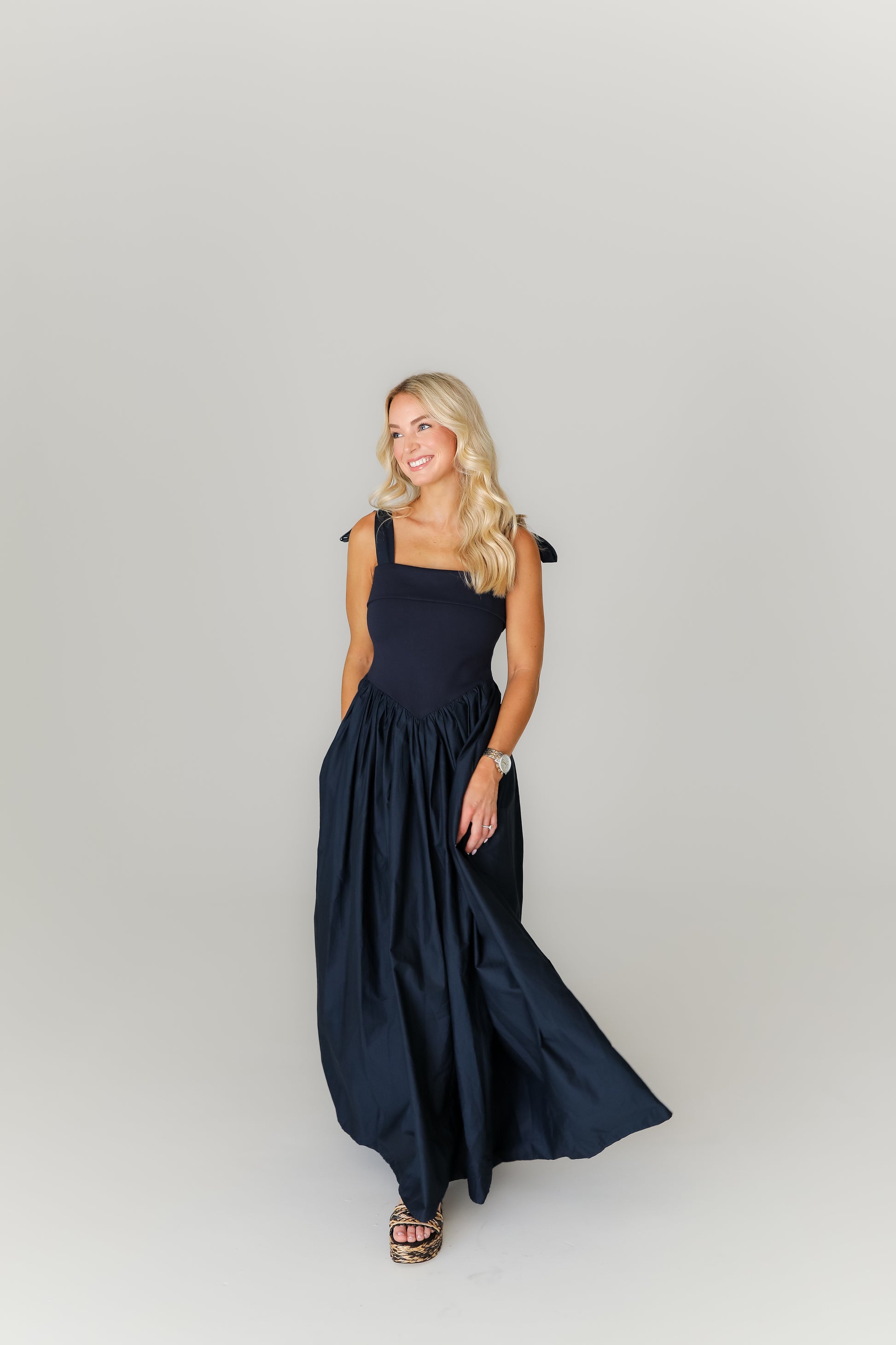 Woman wearing a navy blue dress on a plain background