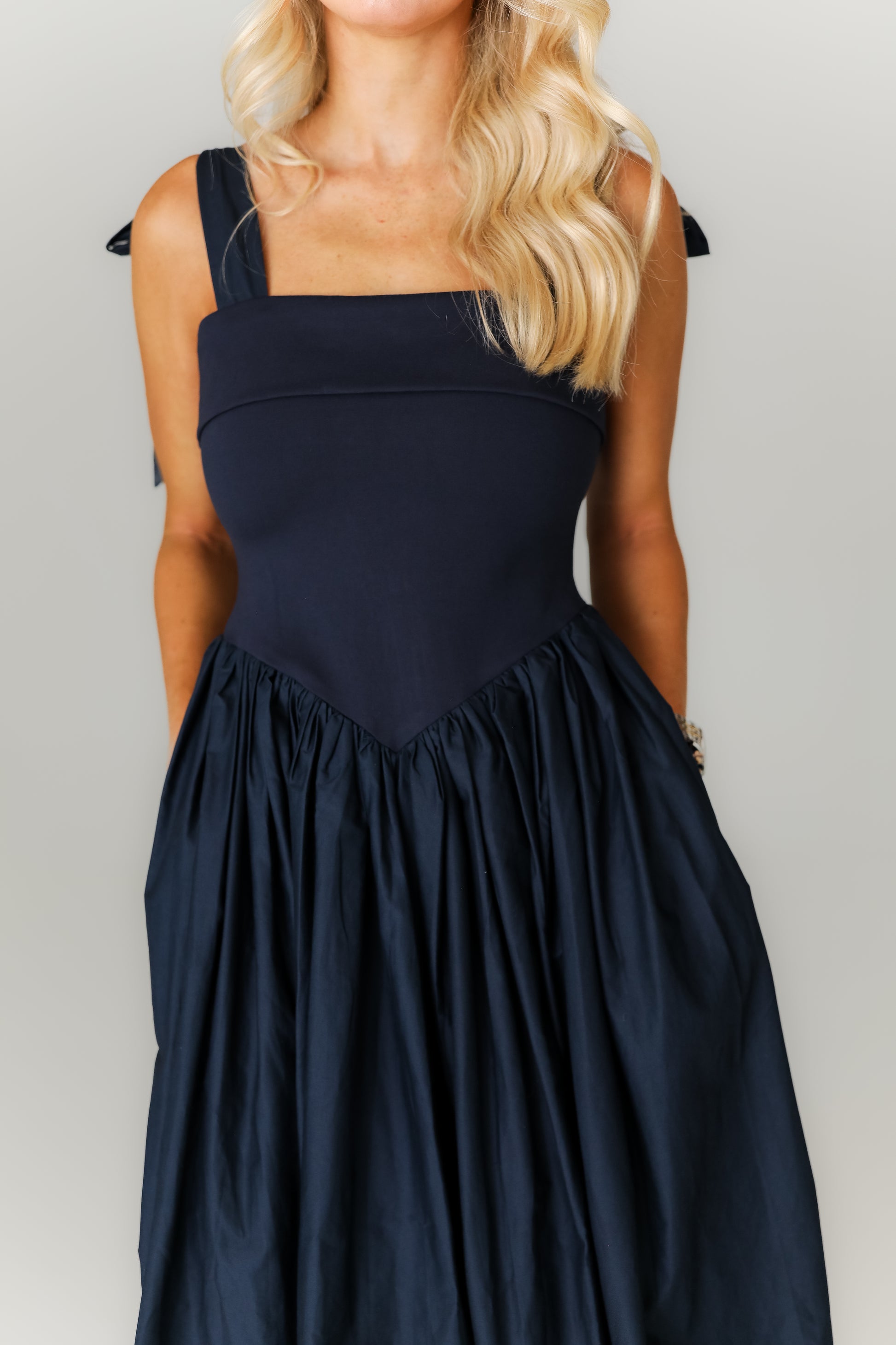 Woman wearing a black sleeveless dress against a plain background