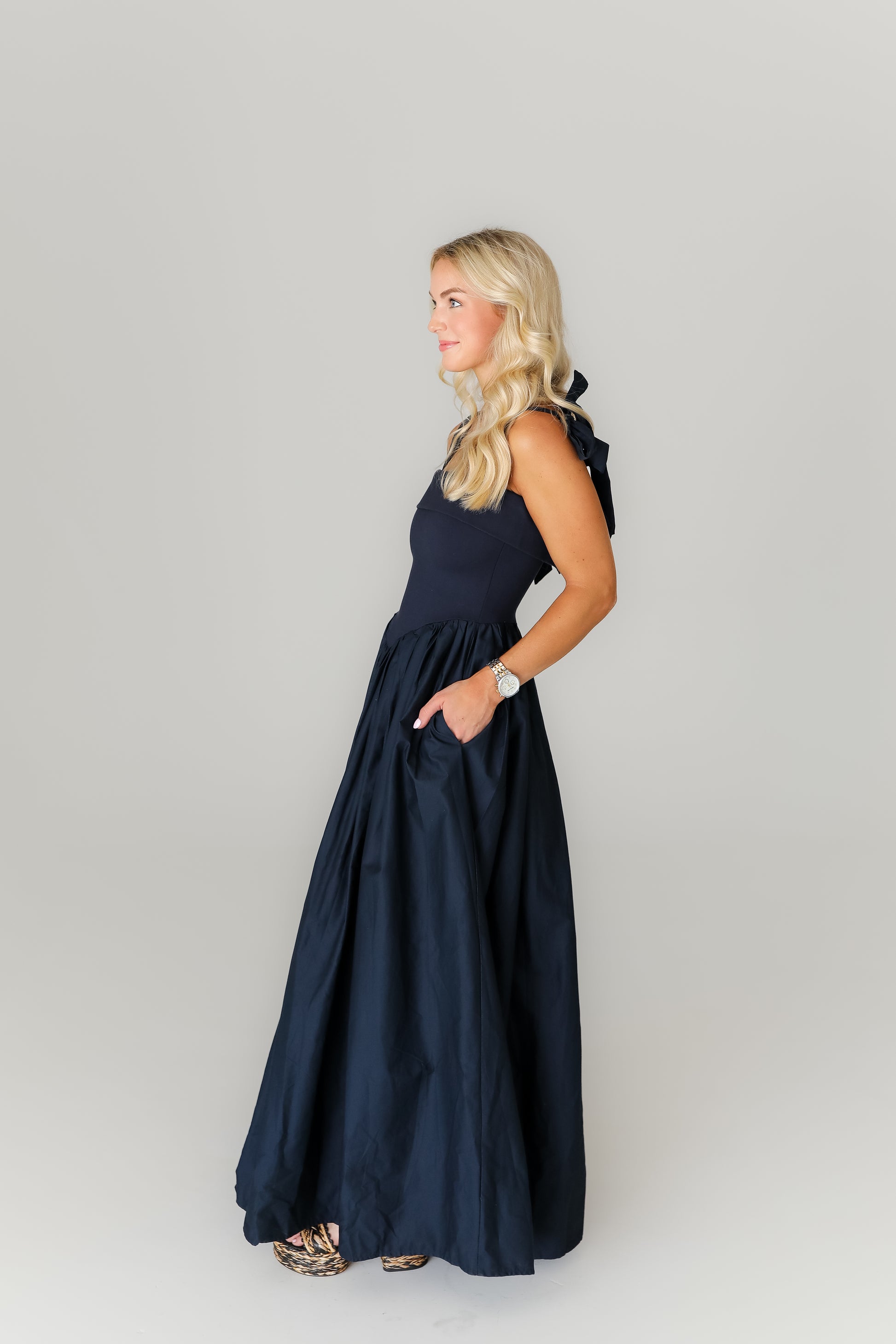 Woman wearing a navy blue dress against a plain background