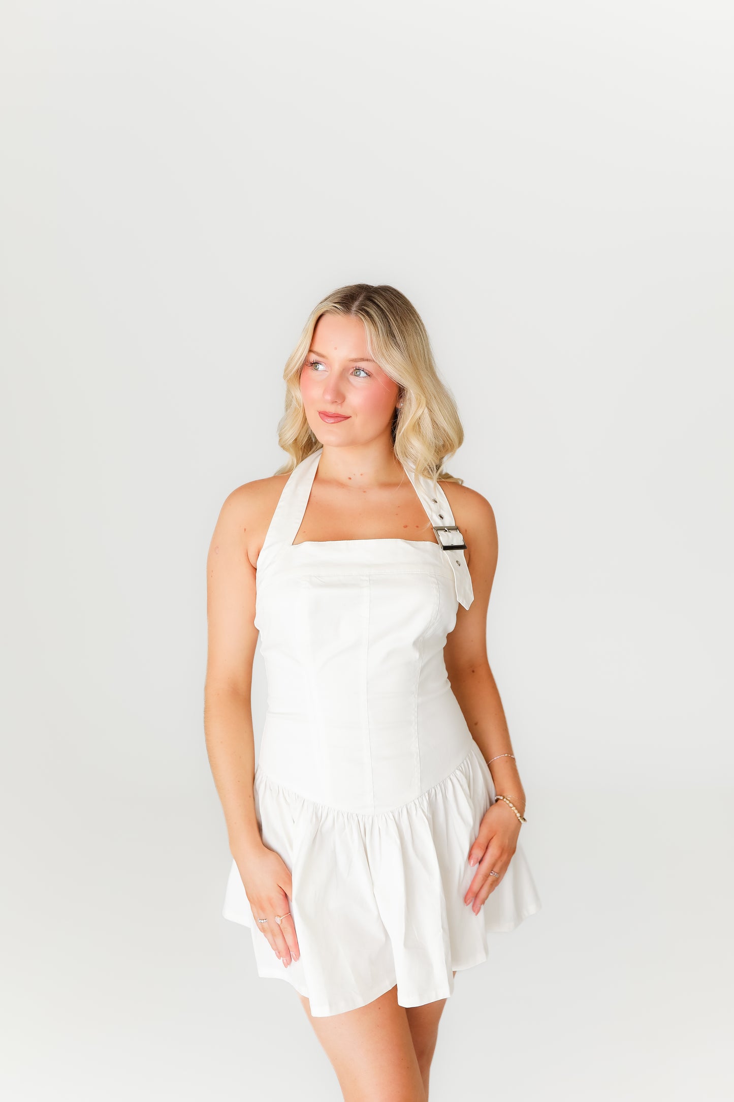 Woman wearing a white dress and brown boots on a plain background