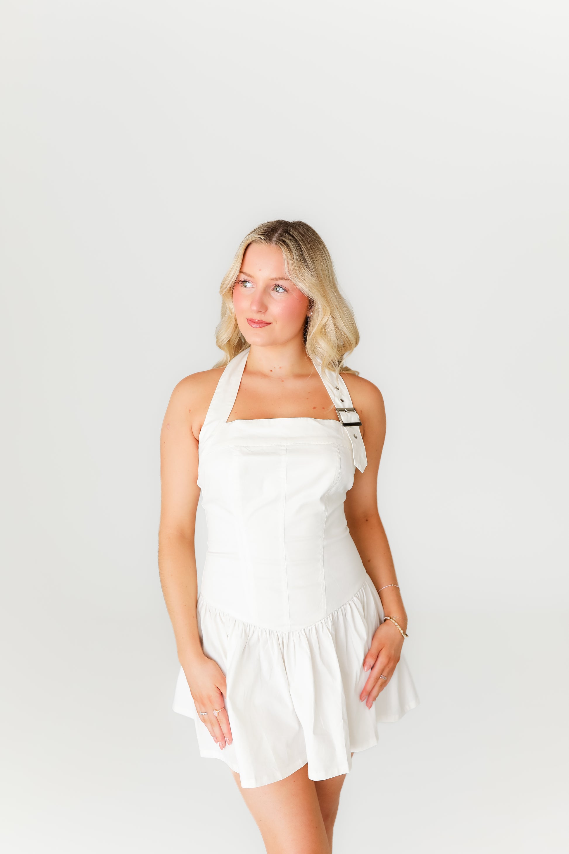 Woman wearing a white dress and brown boots on a plain background