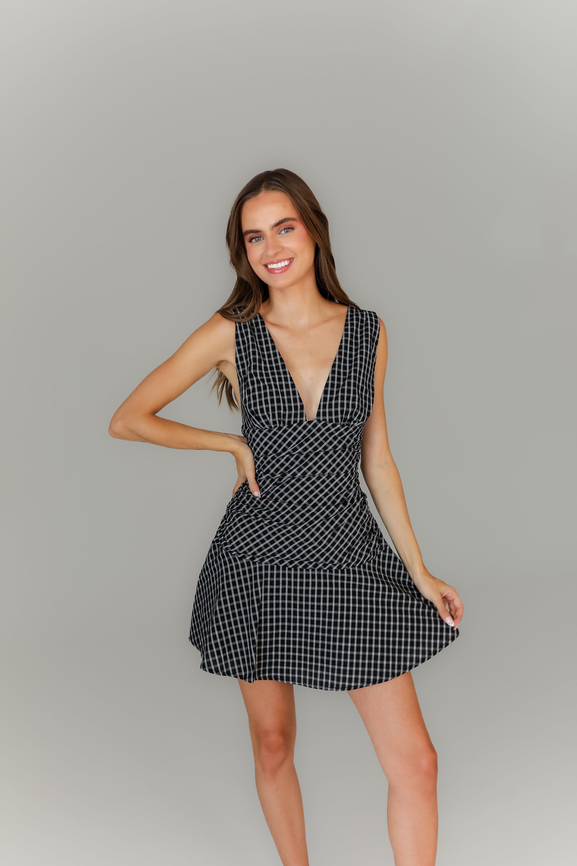 Woman wearing a black and white plaid dress against a gray background