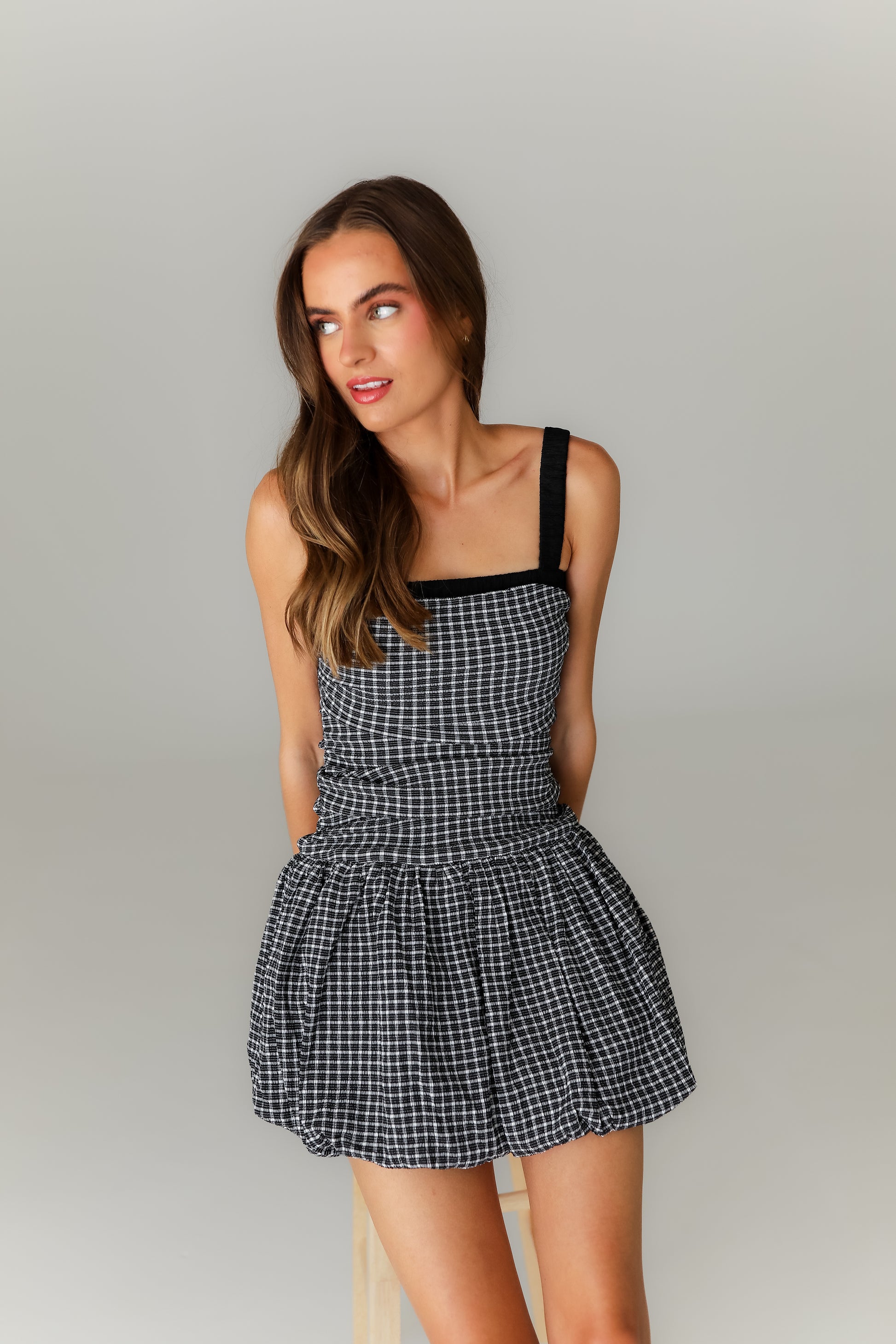 Woman wearing a black and white checkered dress against a plain background