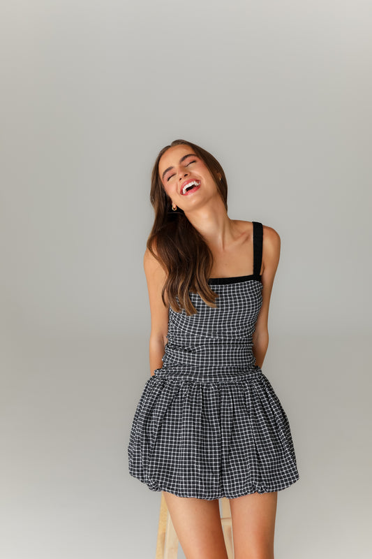 Woman wearing a black and white checkered dress against a plain background